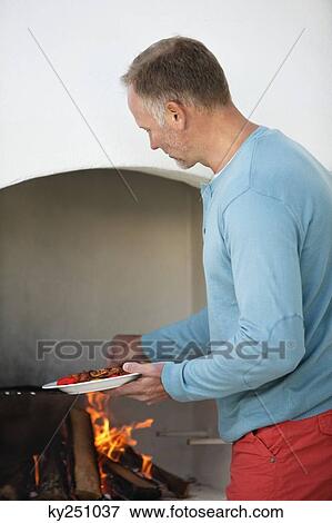 Man cooking kebab in fireplace View Large Photo Image Stock Photo - Man cooking kebab in fireplace. Fotosearch