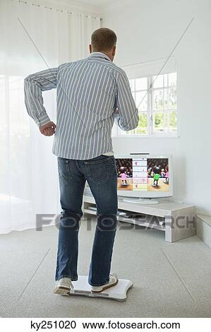 Stock Image - Man doing step aerobics and watching TV. Fotosearch