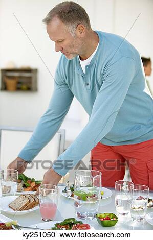 Stock Image - Man having breakfast at a dining table. Fotosearch