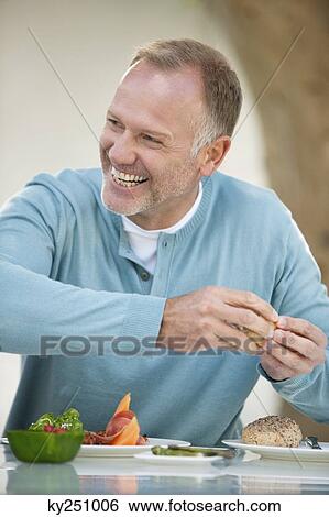 Stock Photograph - Man having breakfast at a dining table. Fotosearch