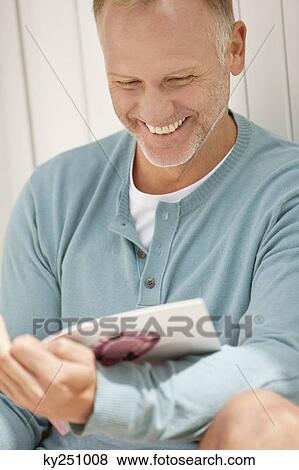 Man reading a magazine and smiling View Large Photo Image Stock Photo - Man reading a magazine and smiling. Fotosearch