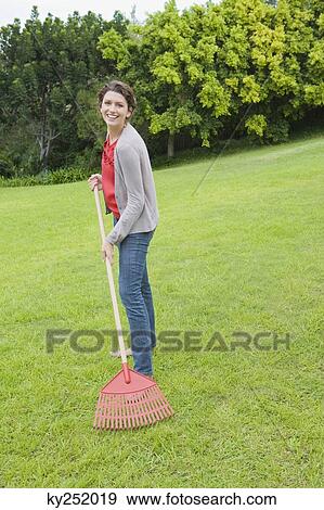 Portrait of a woman raking a lawn View Large Photo Image Stock Photo - Portrait of a woman raking a lawn. Fotosearch