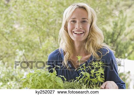 Woman carrying plants and smiling View Large Photo Image Stock Photo - Woman carrying plants and smiling. Fotosearch
