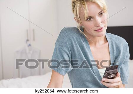 Woman holding a mobile phone and thinking View Large Photo Image Picture - Woman holding a mobile phone and thinking. Fotosearch