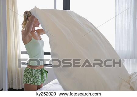 Woman making a bed View Large Photo Image Stock Image - Woman making a bed. Fotosearch