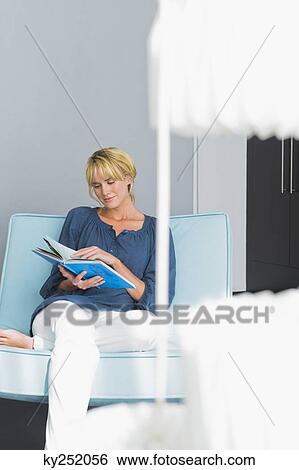 Woman reading a book on a couch View Large Photo Image Stock Photograph - Woman reading a book on a couch. Fotosearch