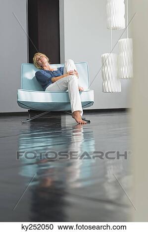 Stock Image - Woman reclining on a couch. Fotosearch