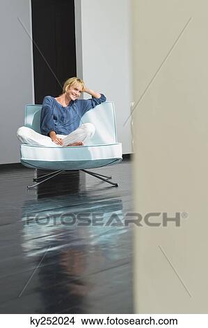 Woman sitting on a couch View Large Photo Image Picture - Woman sitting on a couch. Fotosearch