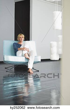 Stock Image - Woman sitting on a couch. Fotosearch
