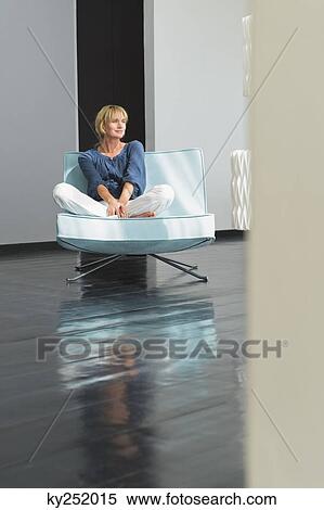 Woman sitting on a couch View Large Photo Image Stock Photography - Woman sitting on a couch. Fotosearch