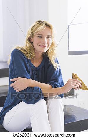 Woman sitting on steps and holding a sandwich View Large Photo Image Stock Image - Woman sitting on steps and holding a sandwich. Fotosearch