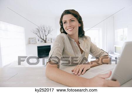 Woman using a laptop and smiling View Large Photo Image Stock Photo - Woman using a laptop and smiling. Fotosearch