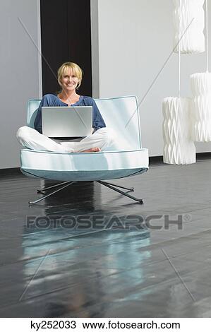 Woman using a laptop on a couch View Large Photo Image Stock Image - Woman using a laptop on a couch. Fotosearch