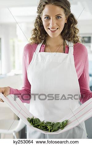 Woman holding spinach leaves in the kitchen View Large Photo Image Picture - Woman holding spinach leaves in the kitchen. Fotosearch