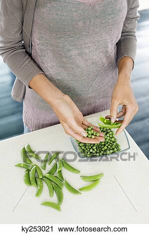 Woman peeling green peas in the kitchen View Large Photo Image Stock Image - Woman peeling green peas in the kitchen. Fotosearch