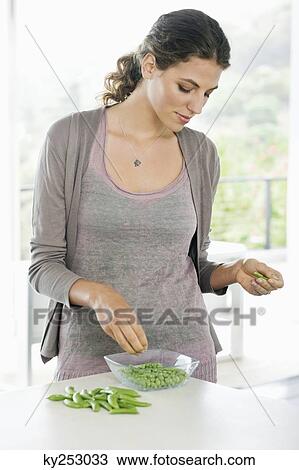 Woman peeling green peas in the kitchen View Large Photo Image Stock Image - Woman peeling green peas in the kitchen. Fotosearch