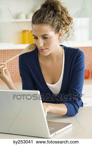 Woman reading a recipe on a laptop in the kitchen View Large Photo Image Stock Image - Woman reading a recipe on a laptop in the kitchen. Fotosearch
