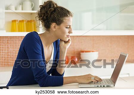 Woman reading a recipe on a laptop in the kitchen View Large Photo Image Stock Photo - Woman reading a recipe on a laptop in the kitchen. Fotosearch