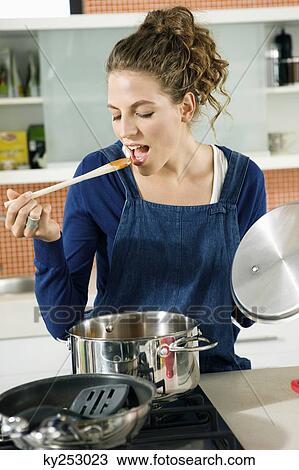 Stock Image - Woman tasting food in the kitchen. Fotosearch
