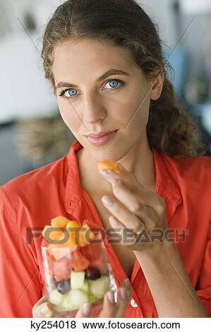 Stock Photo - Portrait of a woman eating fruit salad. Fotosearch