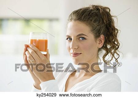 Stock Photo - Portrait of a woman holding a glass of tomato soup. Fotosearch