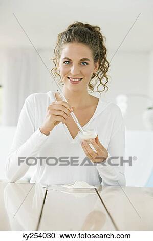 Stock Image - Woman mixing white clay for facial mask. Fotosearch