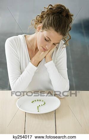 Woman sitting at a table with peas in question mark shape on a plate View Large Photo Image Stock Photo - Woman sitting at a table with peas in question mark shape on a plate. Fotosearch