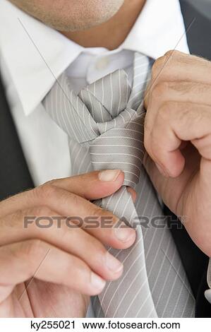 Close-up of a groom adjusting his tie View Large Photo Image Stock Image - Close-up of a groom adjusting his tie. Fotosearch