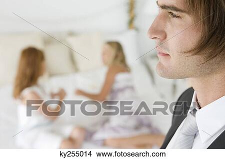 Picture - Close-up of a groom with two girls in the background. Fotosearch