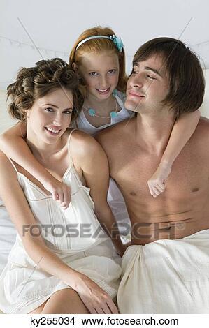 Couple smiling with their daughter on the bed View Large Photo Image Picture - Couple smiling with their daughter on the bed. Fotosearch