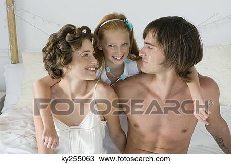 Couple smiling with their daughter on the bed View Large Photo Image Stock Image - Couple smiling with their daughter on the bed. Fotosearch