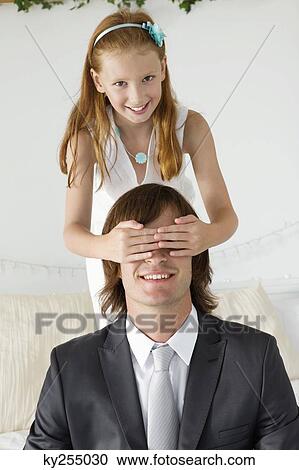 Stock Image - Girl covering man's eyes and smiling. Fotosearch