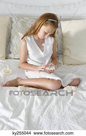Girl holding a flower on the bed View Large Photo Image Picture - Girl holding a flower on the bed. Fotosearch