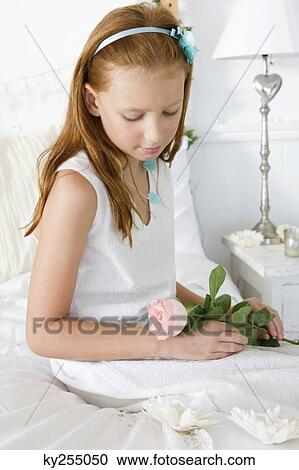 Stock Image - Girl holding a flower on the bed. Fotosearch
