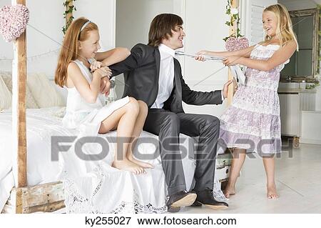 Girl pulling tie of a groom with a girl sitting beside him View Large Photo Image Stock Photo - Girl pulling tie of a groom with a girl sitting beside him. Fotosearch