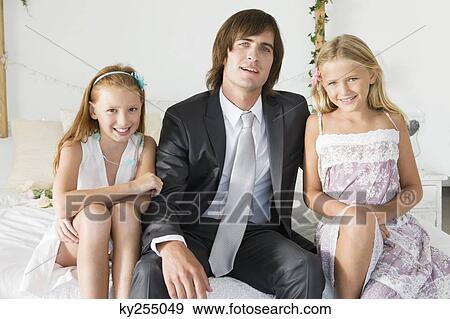 Groom sitting with two girls on the bed View Large Photo Image Stock Photo - Groom sitting with two girls on the bed. Fotosearch