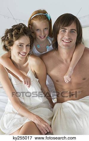 Stock Photo - Portrait of a family smiling on the bed. Fotosearch