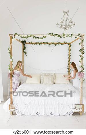 Stock Image - Two girls decorating a bed. Fotosearch