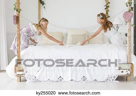 Two girls decorating a bed View Large Photo Image Stock Image - Two girls decorating a bed. Fotosearch