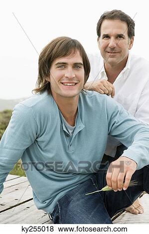 Two men sitting on a boardwalk View Large Photo Image Stock Photo - Two men sitting on a boardwalk. Fotosearch