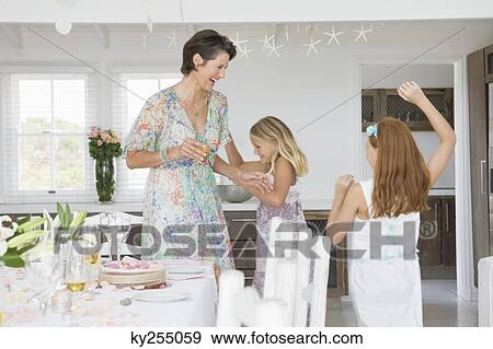 Woman standing with her daughters playing at a dining table View Large Photo Image Stock Photo - Woman standing with her daughters playing at a dining table. Fotosearch