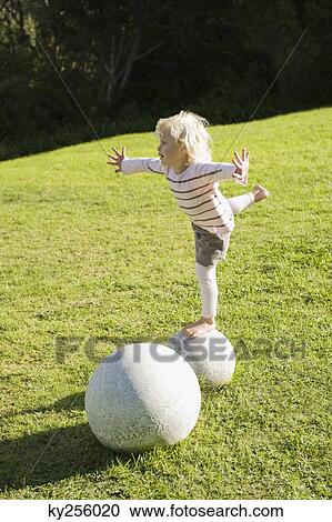 Girl balancing herself on a round stone View Large Photo Image Stock Image - Girl balancing herself on a round stone. Fotosearch