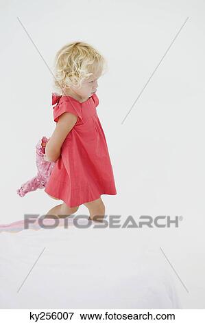 Girl holding a doll and looking serious View Large Photo Image Stock Photo - Girl holding a doll and looking serious. Fotosearch