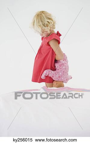Girl holding a doll and looking serious View Large Photo Image Stock Photography - Girl holding a doll and looking serious. Fotosearch