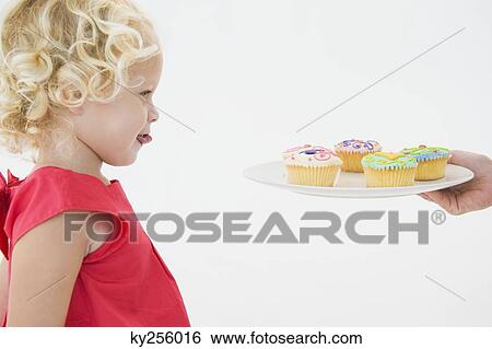 Girl looking at cupcakes View Large Photo Image Stock Photograph - Girl looking at cupcakes. Fotosearch