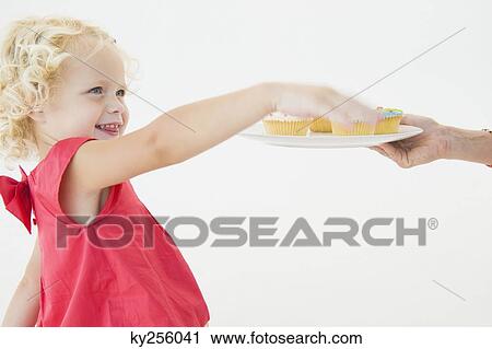 Stock Image - Girl picking up a cupcake. Fotosearch