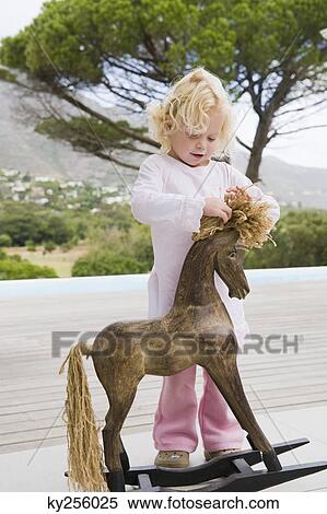 Girl playing with a rocking horse View Large Photo Image Stock Photography - Girl playing with a rocking horse. Fotosearch