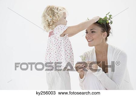 Girl putting a wreath on her mother's head View Large Photo Image Stock Image - Girl putting a wreath on her mother's head. Fotosearch