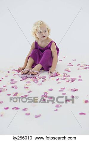 Stock Image - Girl sitting with flower petals scattered around her. Fotosearch