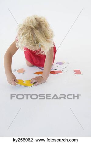 Girl solving a jigsaw puzzle View Large Photo Image Stock Image - Girl solving a jigsaw puzzle. Fotosearch